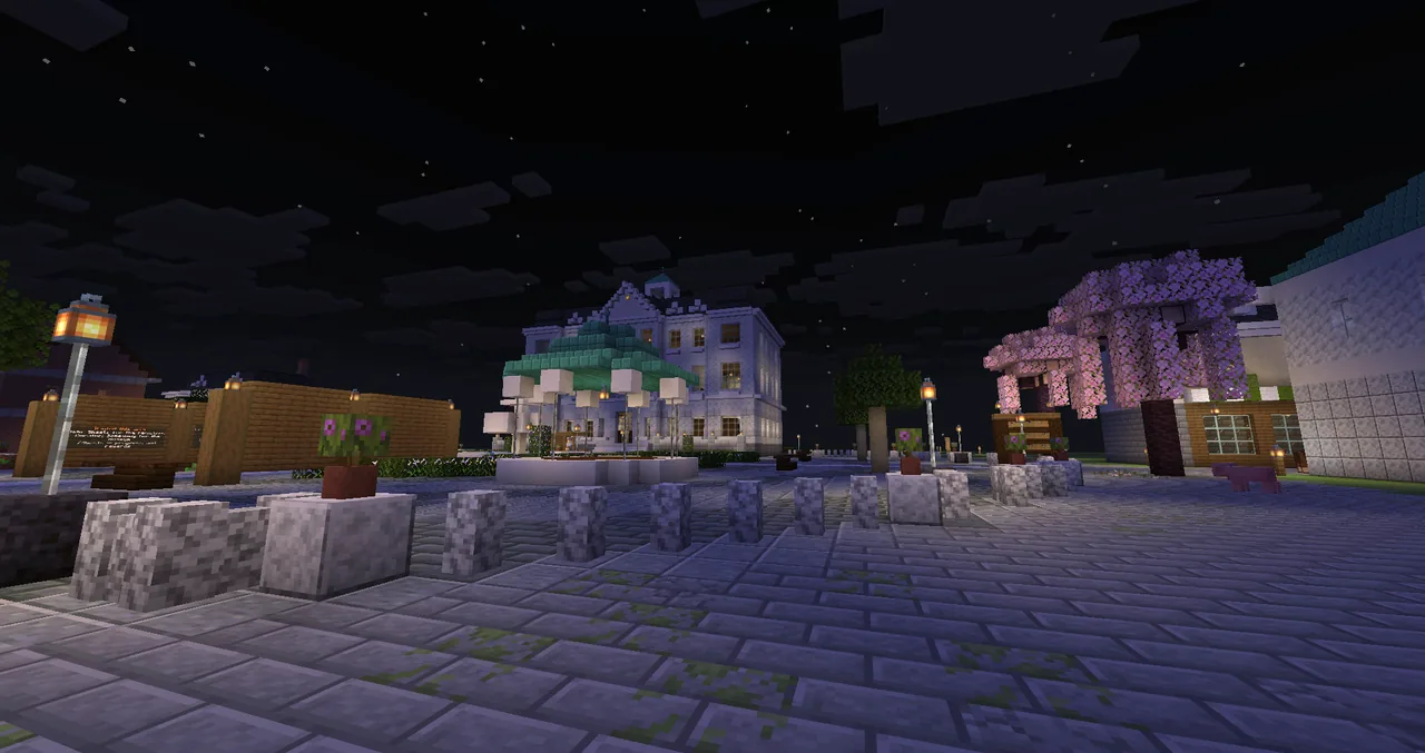 The square at night, lanterns lit, the town hall and the bandstand behind.